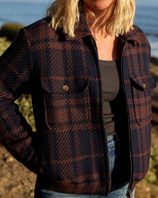 Person wearing a plaid jacket by the beach