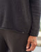 Person wearing a dark gray sweater with a blurred background