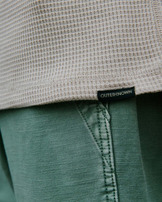 Close-up of a label on a waffle henley with 'Outerknown' branding.