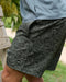 Person wearing black paisley patterned shorts with a blurred background
