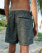 Person wearing paisley patterned shorts on a beach
