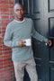 Man wearing green pacifica sweater holding a cup of coffee