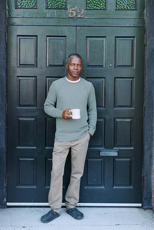 Man wearing green pacifica sweater standing in front of a big door