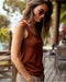 Woman wearing a rust-colored tank top and sunglasses outdoors