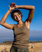 Woman stretching outdoors with a clear blue sky and ocean in the background