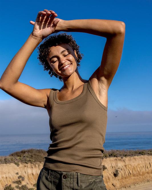Woman stretching outdoors with a clear blue sky and ocean in the background