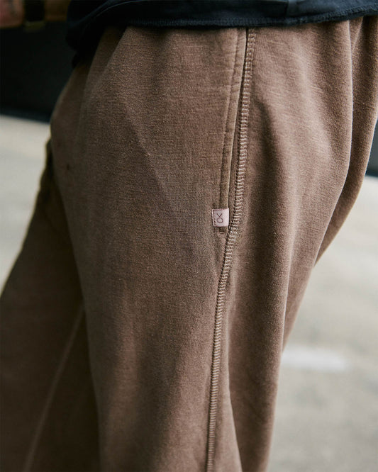 Close-up of brown sweatpants with a brand label on a blurred background