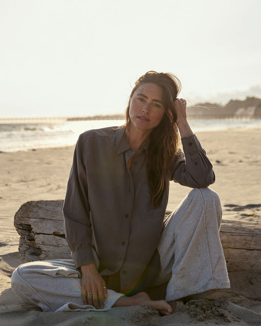 Woman sitting on a log by the beach with a blurred background