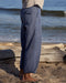 Person wearing blue pants standing on a beach with ocean waves in the background