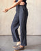 Person wearing dark gray pants standing against a plain background