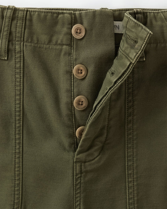 Close-up of green pants with buttons and a brand label on a white background