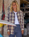 Woman holding a surfboard in a workshop setting