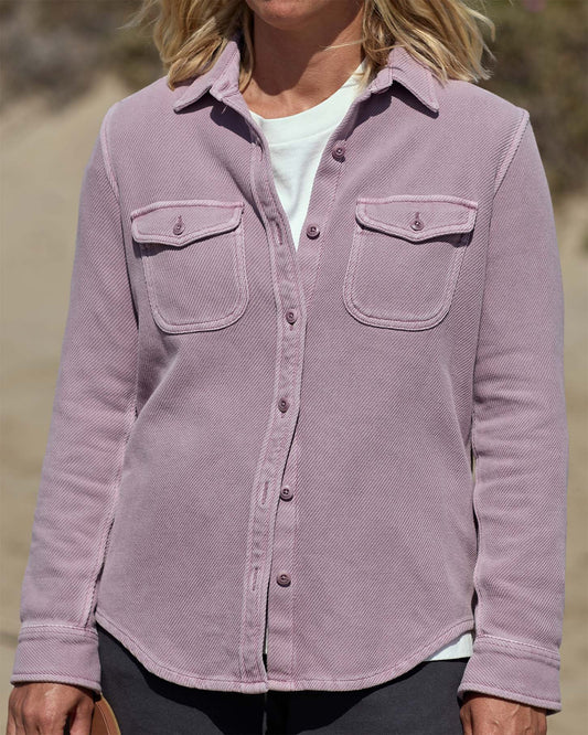 Woman wearing a pastel pink blanket shirt on the beach.