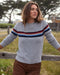 Woman wearing a gray sweater with colorful stripes outdoors