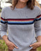 Person wearing a gray sweater with colorful stripes outdoors