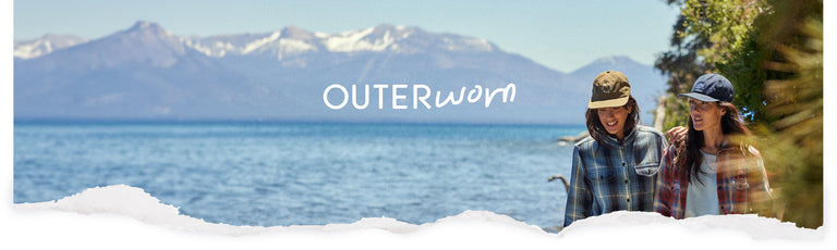 Two women walking along the beach in Lake Tahoe, wearing plaid shirts.