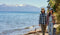 Two people walking along a lakeshore with mountains in the background